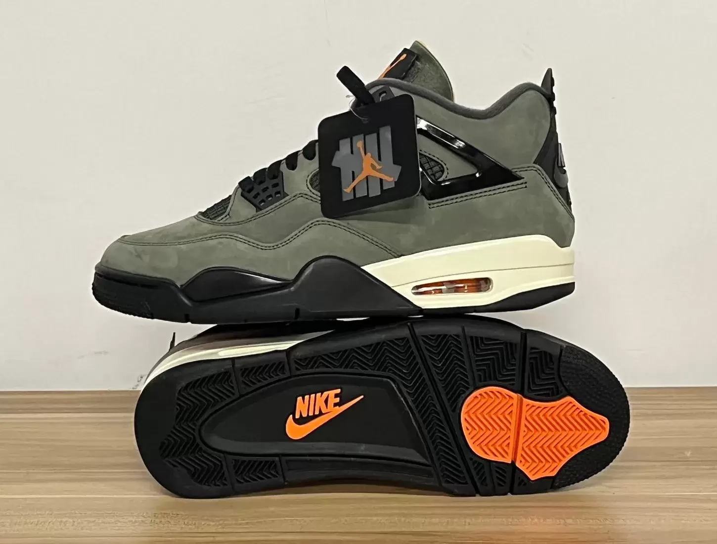 Undefeated x Air Jordan 4 2025 in Deep Green stacked to show outsole with orange Nike logo and black tread. Undefeated x Air Jordan 4 2025 in Deep Green stacked to show outsole with orange Nike logo and black tread.