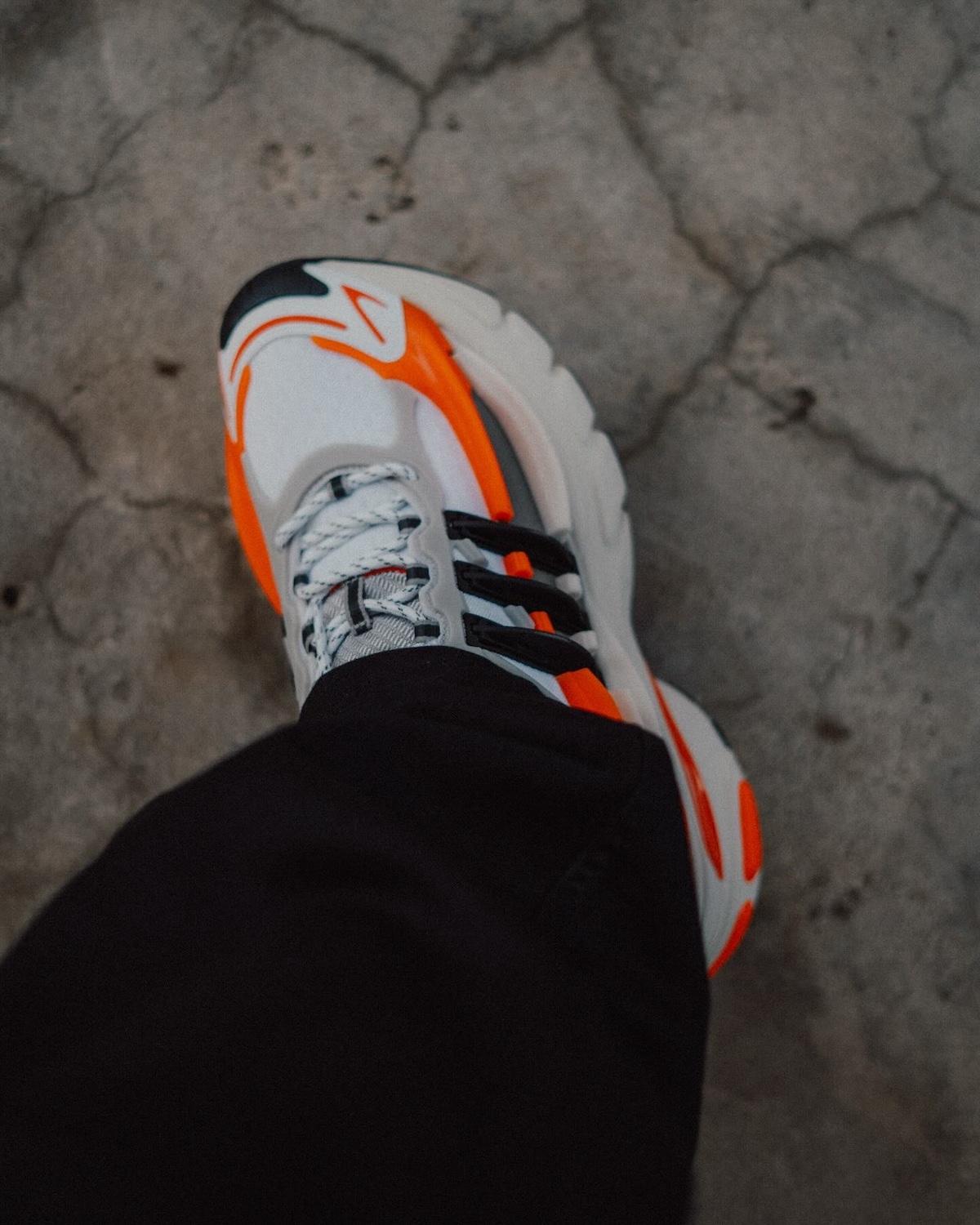 Pharrell x adidas Adistar Jellyfish Virginia Side Profile – A side view of the Pharrell x adidas Adistar Jellyfish showcasing its wavy midsole, TPU cage, and vibrant orange and black accents against a light grey mesh base. Pharrell x adidas Adistar Jellyfish Virginia Side Profile – A side view of the Pharrell x adidas Adistar Jellyfish showcasing its wavy midsole, TPU cage, and vibrant orange and black accents against a light grey mesh base.