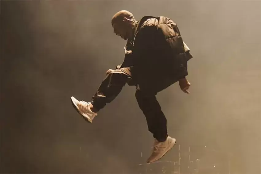 坎耶-維斯特(Kanye West)在 2015 年公告牌音樂頒獎典禮上的表演中途跳下,在舞台上展示了三重白 adidas Ultraboost。 Kanye West performing at the 2015 Billboard Music Awards, wearing Triple White adidas Ultraboost sneakers.