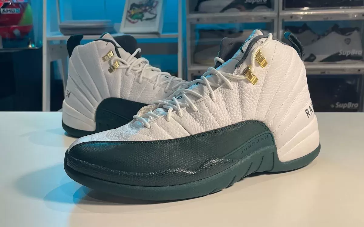 雷-阿倫在密爾沃基雄鹿隊時期穿着的白綠配色的 Air Jordan 12 PE。 Close-up of the Air Jordan 12 「Bucks」 PE, featuring a white leather upper with dark green overlays, gold eyelets, and Ray Allen』s 34 and RAY stitched details.